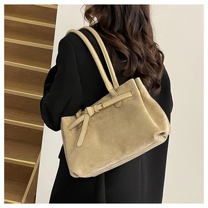 Dettaglio di una borsa tote in pelle opaca beige con cinturino decorativo e fibbia retrò