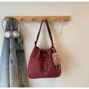 Detail of red checkered canvas tote with drawstring closure and cute plush bear charm