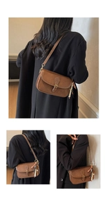 Detail of vintage brown matte crossbody bag with wooden bead charm and flap buckle strap