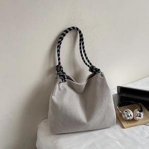 Close-up of beige corduroy tote bag with braided black and white rope handles