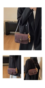 Close-up of vintage brown frosted leather bag with brass buckle and ethnic bead charm