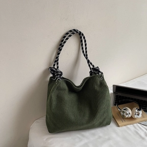 Detail of dark green corduroy tote bag with black and white checkered braided handles