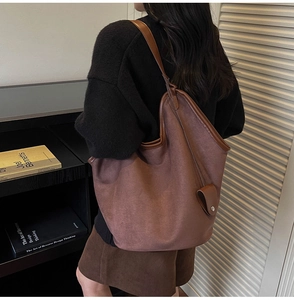 Detail view of brown faux suede tote bag with contrast leather piping and magnetic closure