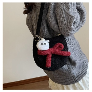 Détail d'un sac à bandoulière en peluche noire avec grand nœud rouge et pendentif mignon