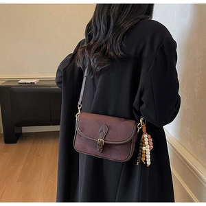 Détail du sac bandoulière en daim marron foncé avec boucle vintage et gland ethnique
