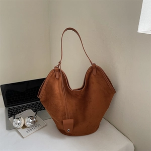 Detail shot of the caramel brown suede tote bag with a matching mini pouch charm