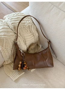 Detail der braunen Retro-Ledertasche mit dekorativem Holzperlen-Anhänger und Riemen