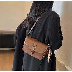 Detailed view of brown matte crossbody bag with retro buckle and decorative bead pendant