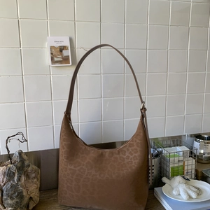 Brown leopard print hobo bag with matte suede texture in a cozy indoor setting