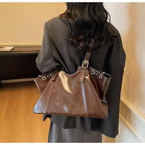 Detailed macro view of the glossy dark brown leather bag with silver metallic eyelets