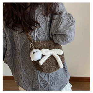 Sac bandoulière en peluche marron avec un grand nœud polaire blanc porté par un mannequin