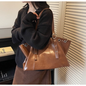 Brown vintage leather tote bag styled on model shoulder for winter fashion commute