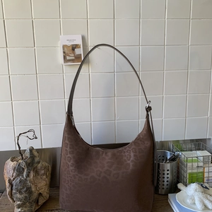 Detailed close-up of brown leopard embossed suede hobo bag on a wooden surface