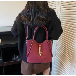 Close-up of matte burgundy tote bag showing suede texture and gold metal bar lock