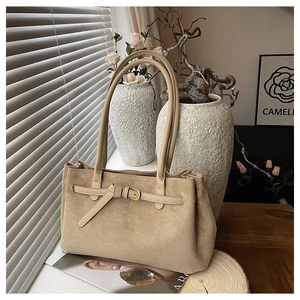 Dettaglio ravvicinato della borsa tote in pelle scamosciata beige con fibbia e pieghe