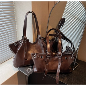 Detail of dark brown leather tote bags featuring metallic eyelets and strap decorations