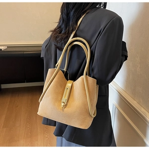 Detail of camel suede tote bag featuring a gold metal buckle and parallel tube handles