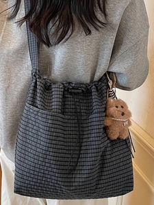 Minimalist grey plaid canvas crossbody bag with drawstring closure and plush pendant