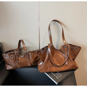 Detail view of brown leather tote bags with metal eyelets and decorative buckles