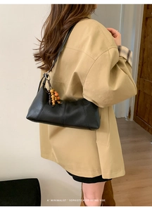 Detail der schwarzen Leder-Tasche mit bunten Holzperlen-Quasten an einem Model