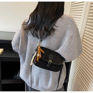 Détail du sac à bandoulière mat vintage avec glands en perles colorées et boucle dorée