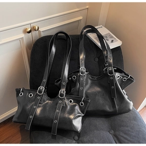 Close-up of black glossy leather tote and underarm bags with punk style silver eyelet studs
