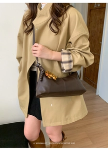 Modell mit dunkelbrauner Retro-Leder-Achseltasche und Holzperlen-Anhänger-Detail