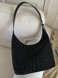 Chic black leopard print hobo shoulder bag on a cozy cream-colored sofa in home setting