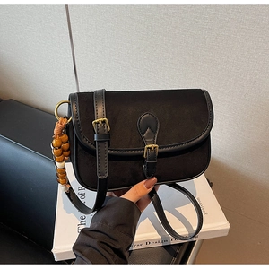 Détail du sac bandoulière vintage noir mat avec texture suède et boucle métallique