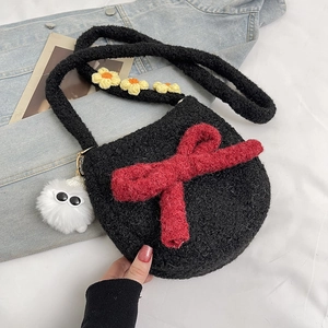 Détail d'un sac bandoulière en peluche noire avec nœud rouge et fleurs brodées