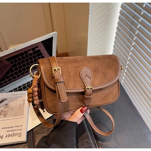 Détail du sac bandoulière en daim marron avec pendentif en perles de bois vintage