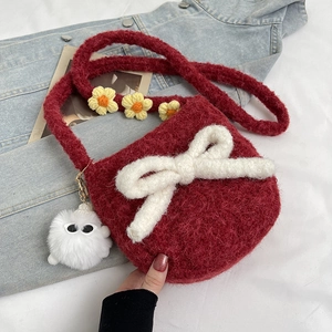Détail d'un sac bandoulière en peluche rouge avec un grand nœud blanc et sangle fleurie