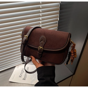 Détail du sac bandoulière vintage en daim marron avec boucle dorée et pompon