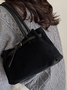 Borsa a tracolla minimalista in pelle scamosciata nera con fibbia dorata su maglione grigio