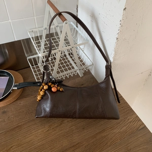 Detail der dunkelbraunen Leder-Hobo-Tasche mit Holz- und orangefarbenem Perlenanhänger