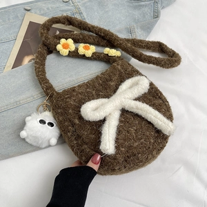Détail d'un sac bandoulière en peluche marron avec nœud blanc et sangle fleurie