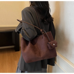 Detail of dark brown suede tote bag with knot strap and mini accessory bag attached