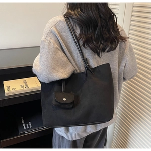 Detail of minimalist black matte tote bag with shoulder strap knot and small side pouch