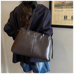 Detailansicht der dunkelbraunen Leder-Shopper-Tasche mit Markenplakette und Seitendetails
