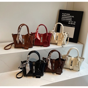 Detail of multi-color leather bucket bags with silk scarves and metal hardware