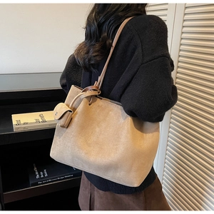 Detailed side view of beige suede tote bag with small detachable coin purse charm