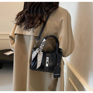 Detail of black leather bucket bag with silver clasp and geometric silk scarf handle