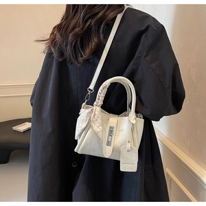 Detail of cream bucket bag with lychee texture, silk scarf, and detachable strap on model