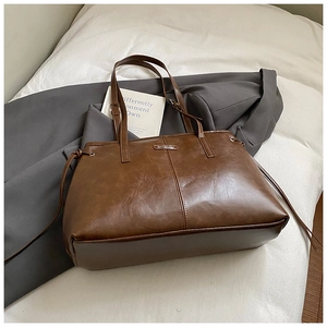 Nahaufnahme der braunen Retro-Ledertasche mit Silberlogo und seitlichem Kordelzug