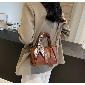 Brown leather bucket bag with decorative plaid scarf and fashion tag detail