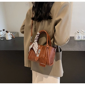 Close-up of brown leather bucket bag with silver buckle and decorative silk scarf detail