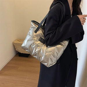 Detail of silver metallic puffer tote bag with quilted texture and fashion leather tag