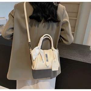 Close-up of cream PU bucket bag featuring elegant metal buckle and silk scarf detail