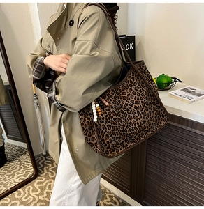 Close-up of leopard print tote bag with beaded charm and dark brown trim detail