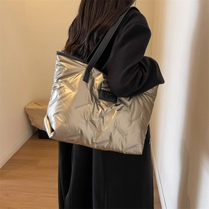 Close-up of metallic champagne quilted tote bag with fashion label and sleek black straps